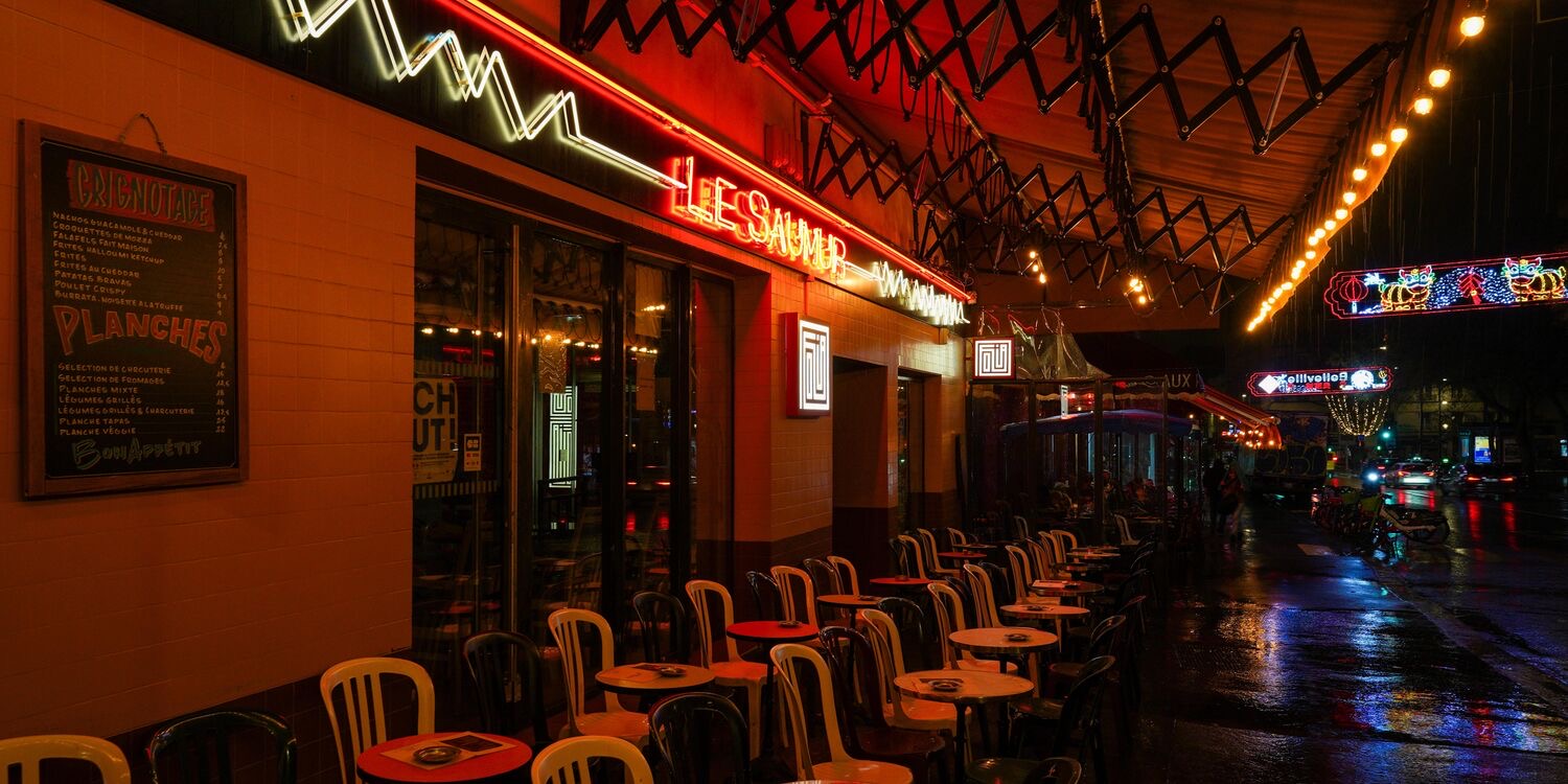 Façade du bar Le Saumur la nuit, 10 rue de Belleville Paris 20 — néon rouge, terrasse animée